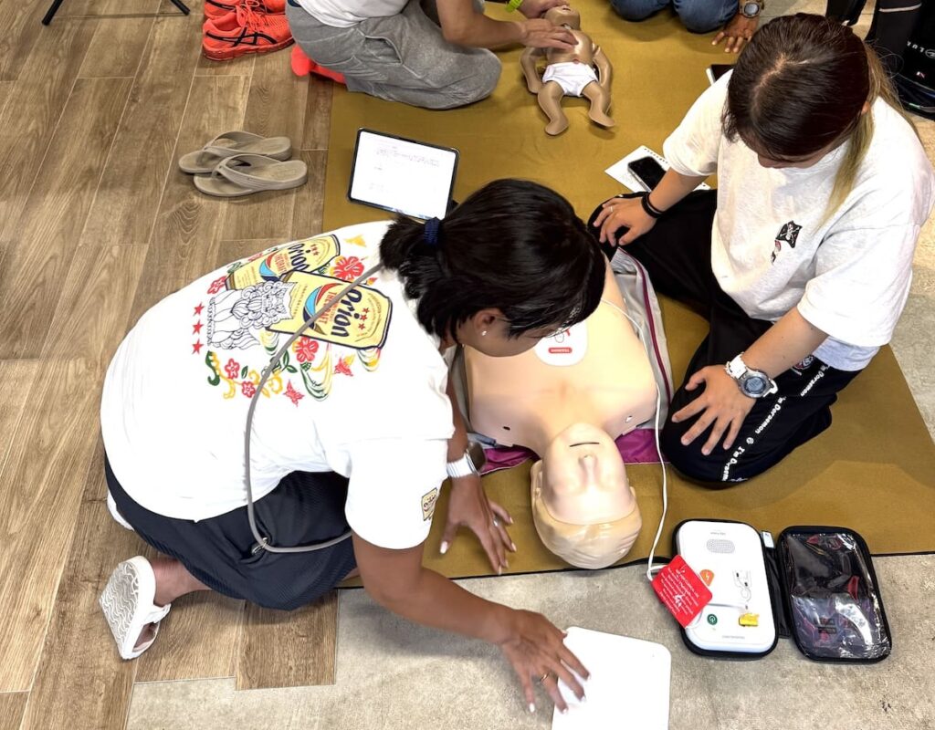 AEDトレーナーと成人マネキンを使って心肺蘇生(CPR)を練習しているMOANAのEFR講習の様子