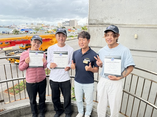 2024年12月のPADIインストラクター試験(IE)に合格した受講生3名が、コースディレクター松谷勇馬と笑顔の記念撮影をしている様子。